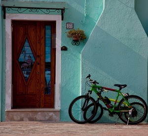 porta, biciclette, numero, fiori, vaso, portone, ruote, vetro, verde, legno, muro, due, trentasette, gradino, giallo, rombo, casa, scalino, campanello, azzurro, camino