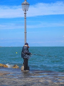 lampione, mare, pescatore, canna, pesca, uomo, acqua, scogli, azzurro, cielo, pescare, giacca, nuvole, cappello, lenza, berretto, celeste
