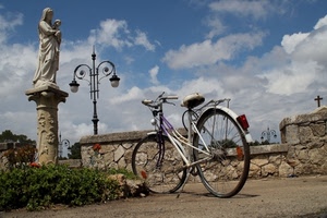 bicicletta, nuvole, statua, cielo, lampione, ruote, colonna, croce, lampioni, muro, madonna, fiori, manubrio, bici, aiuola, erba, piante